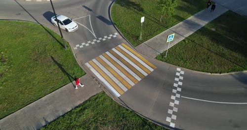 White Car Stops in Front of a Pedestrian Crossing a Girl Crosses the Road