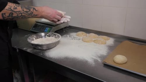 Closeup of a Chef Forming Round Burger Buns From Dough in an Industrial Kitchen