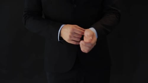 Confident young businessman in suit adjusting tie preparing for work in office