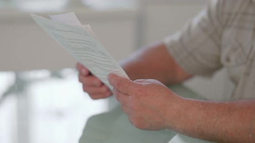 Nahaufnahme der Hände eines Mannes, der einige Dokumente hält