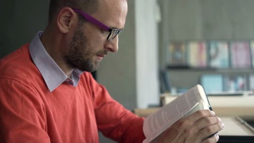 Man Reading a Book at Table Indoors