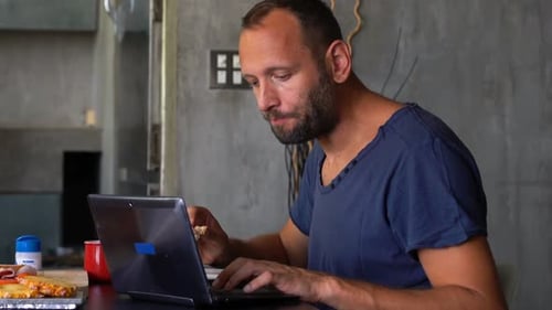 Man Working on Laptop While Eating Lunch Indoors