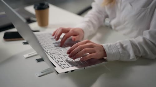 Woman Typing on Laptop in Office Environment