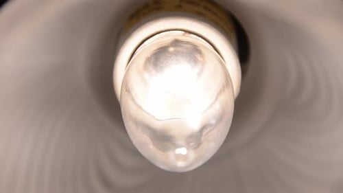Closeup of tungsten chandelier light bulb flickers inside light fixture and dies