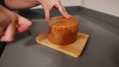 Female cutting cheese with knife on wooden table. Close up