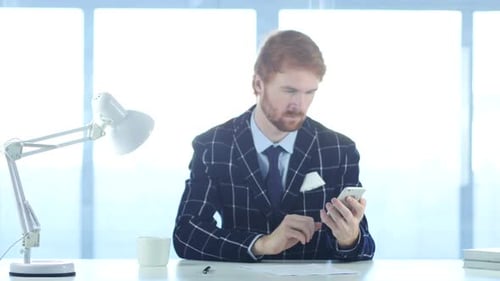 Using Smartphone for Online Browsing Man with Red Hairs