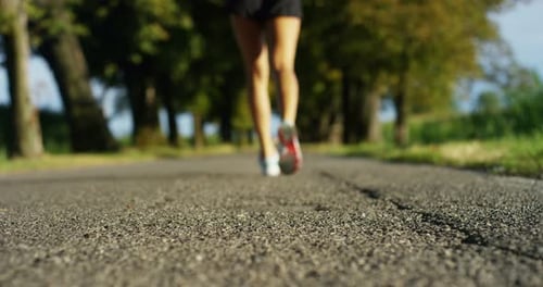 feet and legs girl jogging and running in a street with trees and nature, for music and run slow