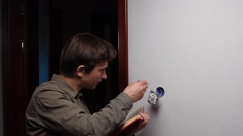 Man Installing Electrical Outlet with Instruction Manual