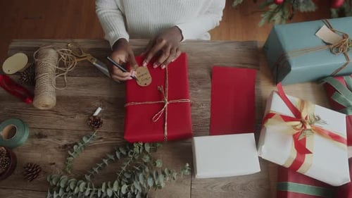 Person Wrapping Christmas Present at Wooden Table