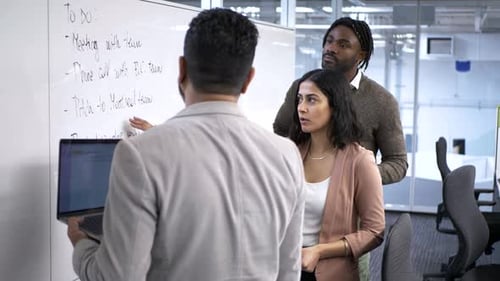 Business People Reviewing to Do List at Whiteboard in Office Meeting 2529 Years