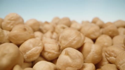 A pile of raw chickpeas is drying against the blue sky. Dolly slider extreme close-up.