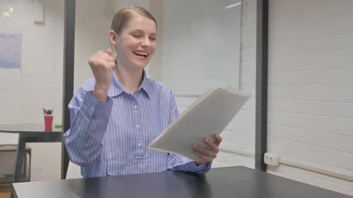 Excited Woman Reviews Documents in Office Setting