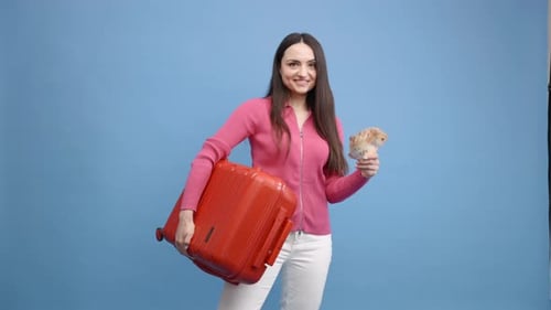 Woman Holds Money, Orange Suitcase Against Blue Background
