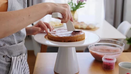 Woman Spreads Frosting on Cake in Bright Kitchen