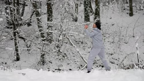 Woman Throwing and Kicking Snowball in Snowy Woods