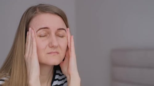 Up Close A Woman with a Severe Headache Holding Her Head with Her Hands