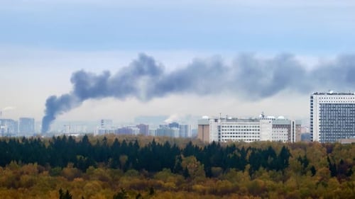 Smoke from a fire over the roofs of city buildings, daytime timelapse