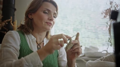 Woman in Retro Clothes Crochets Cup Holder Near Big Window
