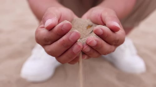 Sand Flowing Through Hands on the Beach