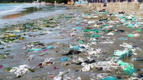 Aerial flying over very polluted beach full of dirty plastic trash