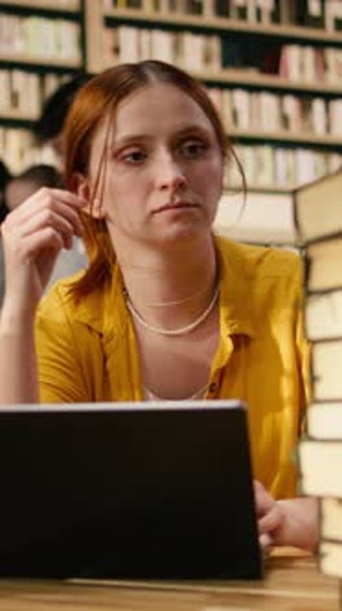 Vertical Video Worried Young Woman Studying Materials on Laptop at Library Table