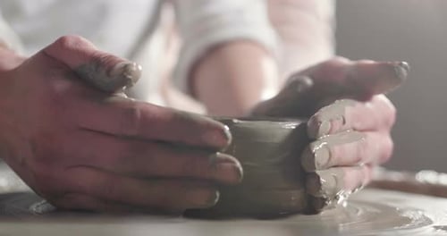 Adult and Child Sculpting Clay Together on Wheel
