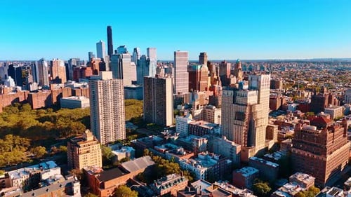 Flying over the vast panorama of New York, USA. Bright sun lights the facades of the high-rises.