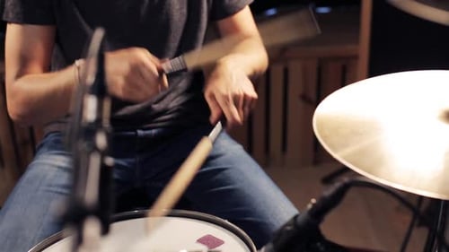 Energetic male musician playing snare drum and hi hat cymbal live at a concert