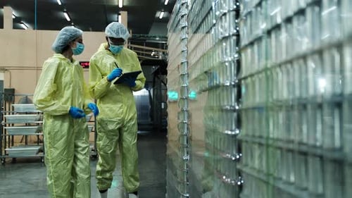 Deux superviseurs inspectent la qualité des contenants utilisés dans la fabrication d'aliments en conserve.