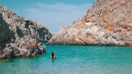 Girl emerging from turquoise waters in a cove beach