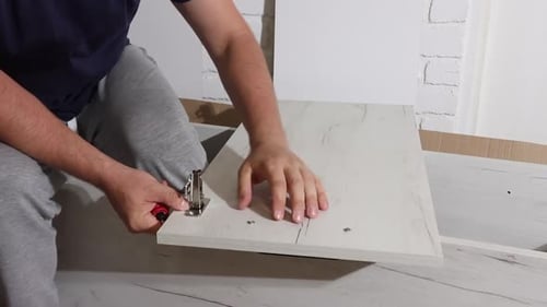 Der Mann repariert den Schranktürgriff mit Bolzen. Es funktioniert mit einem Schraubenzieher.