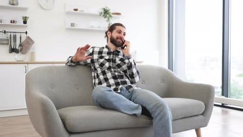 Young Man Talking on Phone While Sitting on Couch