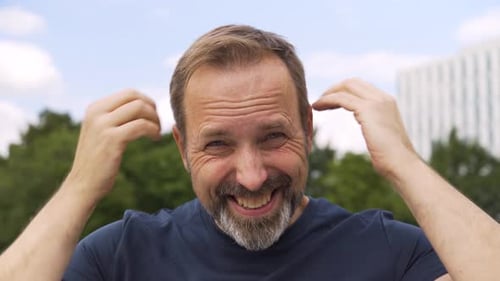 Man Scratching Head in City Park
