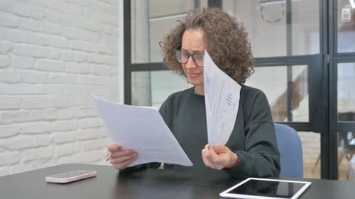 Woman Upset While Reading Documents in Office