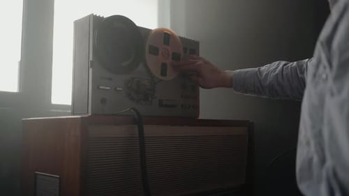 Man Adjusting Vintage Reel-to-Reel Tape Recorder