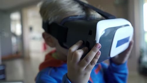 Blond Boy Playing with Virtual Reality Headset Indoors