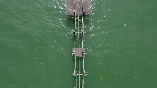 Elevated viewpoint revealing dilapidated wooden bridge above tranquil sea