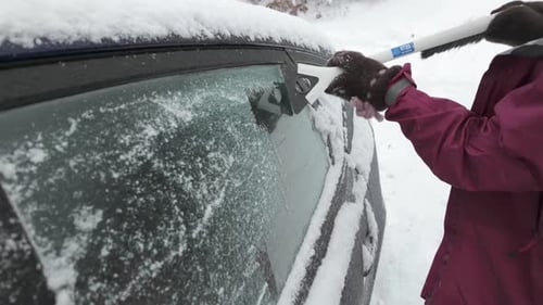 A Hand Scraping Ice Off the Surface of the Car - Close Up