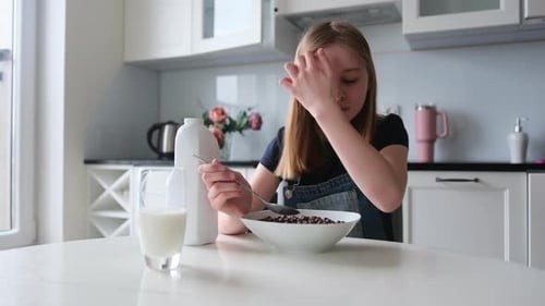 Girl Eats Cereal at Kitchen Table