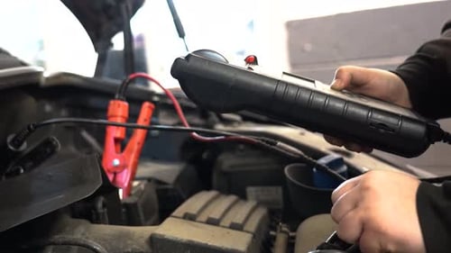 A mechanic tests a vehicle battery