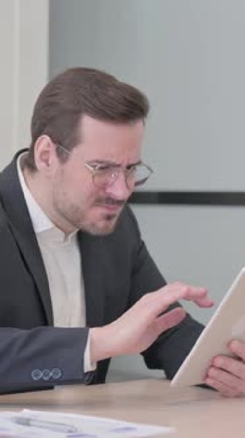 Businessman Using Tablet Expressing Disappointment in Office