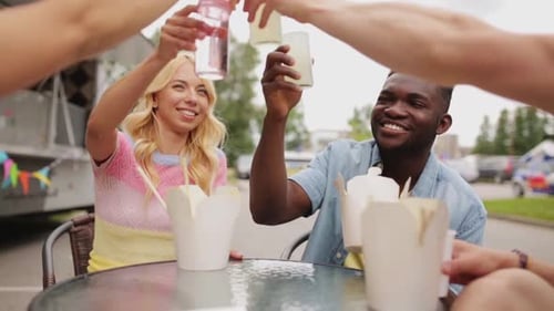 Friends Toasting Drinks at Outdoor Food Truck Table