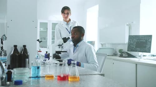 Zwei Wissenschaftler in Uniform schauen unters Mikroskop und diskutieren im Labor über Wunder