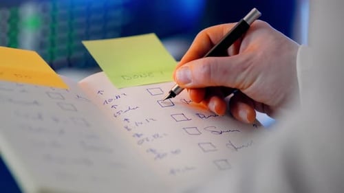 Hand Checks Off Task List with Pen