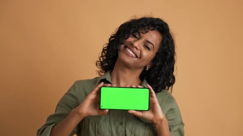 Nette asiatische junge Dame lächelt und zeigt den Telefonbildschirm