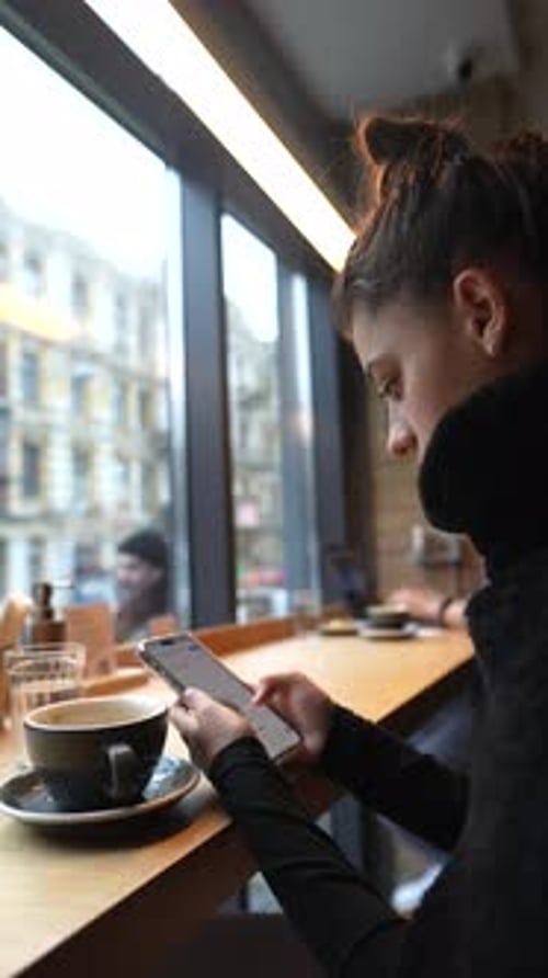Close Up Portrait of Young Beautiful Girl Drinking Coffee with Smartphone in Hands