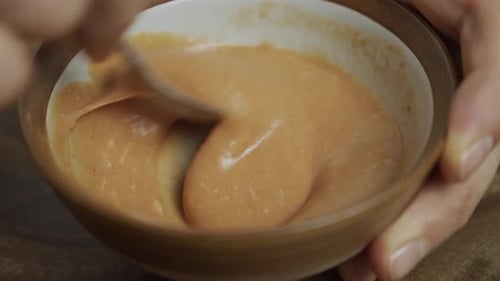 Mixing cheeseburger sauce in small bowl by hand with spoon. Slow motion