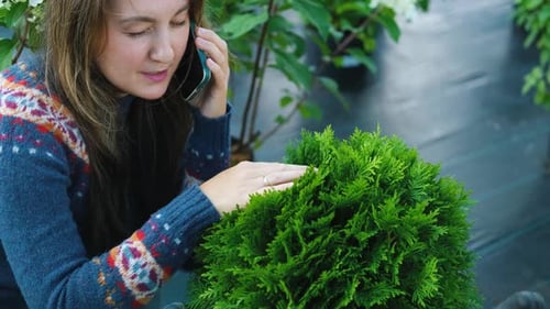 femme en gros plan parlant au téléphone assise parmi les plantes du magasin