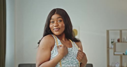 Una joven afroamericana con cabello largo y castaño en ropa deportiva demuestra positividad corporal