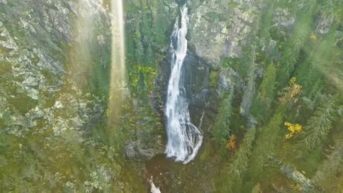 Overhead View Of Majestic Waterfalls With Sunrays In Wild Forest Of Sweden During Sunset.